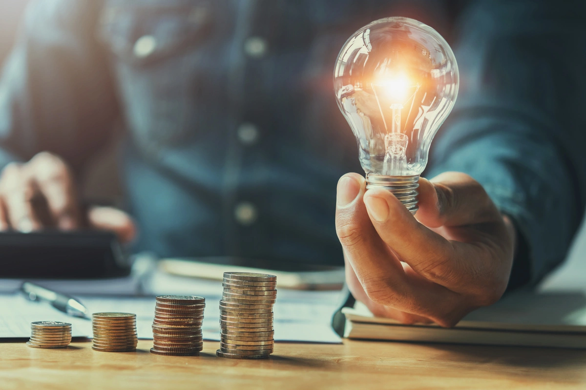 A coins on the table and a man holding a lamp in his hand